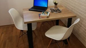 A small wooden table with a laptop, two white chairs, and a few books.