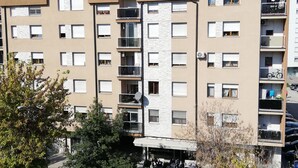 A multi-story residential building with balconies, a ground-level entrance, and a visible sign indicating a commercial space below.