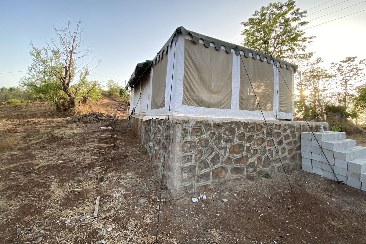 A stone building with a covered porch, surrounded by dry vegetation and a clear sky.