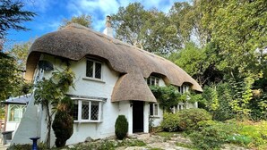 Ein traditionelles Haus mit einem Reetdach und einem steinbelagten Weg zum Eingang.