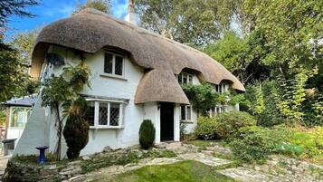 A traditional thatched-roof house with a stone pathway leading to the entrance.