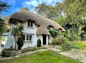 A traditional thatched-roof house with a stone pathway leading to the entrance.