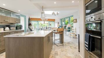 A modern kitchen with a large island, stainless steel appliances, and a view of the garden.