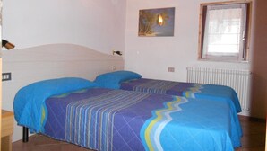 Ein Schlafzimmer mit zwei Betten, einem Bild, einem Fenster und einer Heizung.
