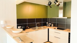 A modern kitchen with a wooden countertop, a sink, a stove, and a green wall. - Beautiful renovated townhouse in the heart of Arago (Les Sables-d'Olonne)