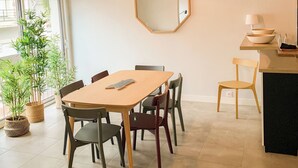 A dining area with a wooden table, chairs, a hexagonal mirror, and potted plants. - Beautiful renovated townhouse in the heart of Arago (Les Sables-d'Olonne)