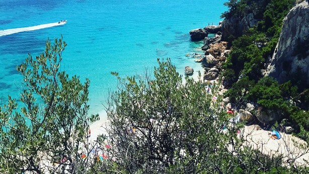 A coastal landscape with a clear blue sea, rocky cliffs, and a beach. - INAH Boutique Rooms (Dorgali)