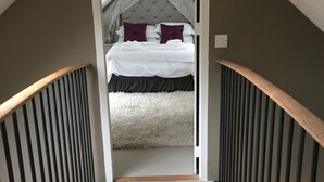 A narrow staircase leading to a bedroom with a bed, a white wall, and a red heart-shaped decoration on the floor. - Characterful Home in beautiful surroundings of Surrey Hills (Bramley)