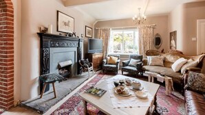 A cozy living room with a fireplace, comfortable seating, and a television. - Characterful Home in beautiful surroundings of Surrey Hills (Bramley)