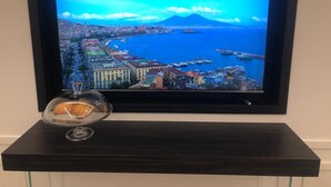 A framed TV displaying a coastal cityscape with a mountain, a marina, and buildings. - Umberto34 - Luxury Home (Naples)