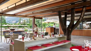 Ein Außenbereich zum Essen mit Tischen, Stühlen und einer Bar, mit Blick auf die Berge.