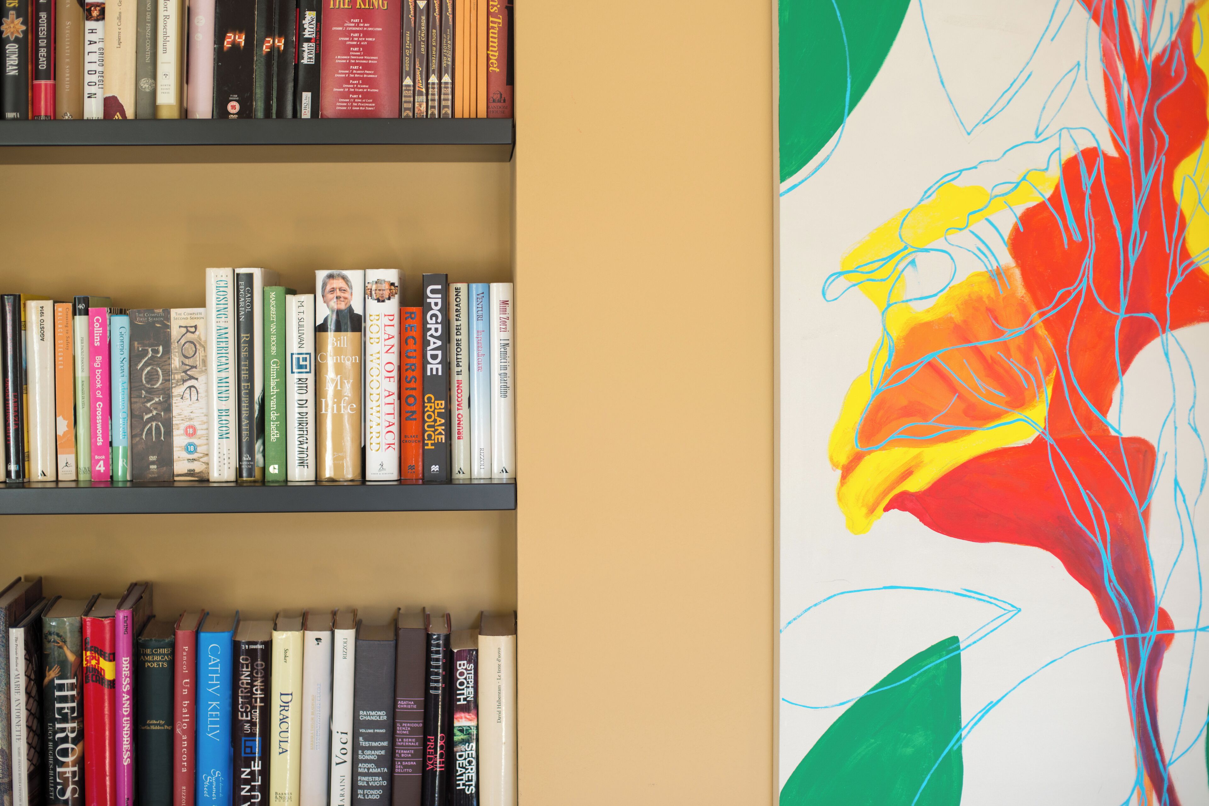 Une bibliothèque remplie de livres et un tableau abstrait aux couleurs vives accroché au mur.