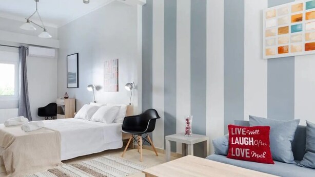 Ein modernes Schlafzimmer mit Bett, Nachttischen, einem Sessel und einer Couch, sowie einem motivierenden Kissen.