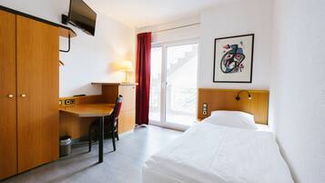 Een hotelkamer met een bed, een bureau, een stoel, een televisie en een raam met uitzicht.