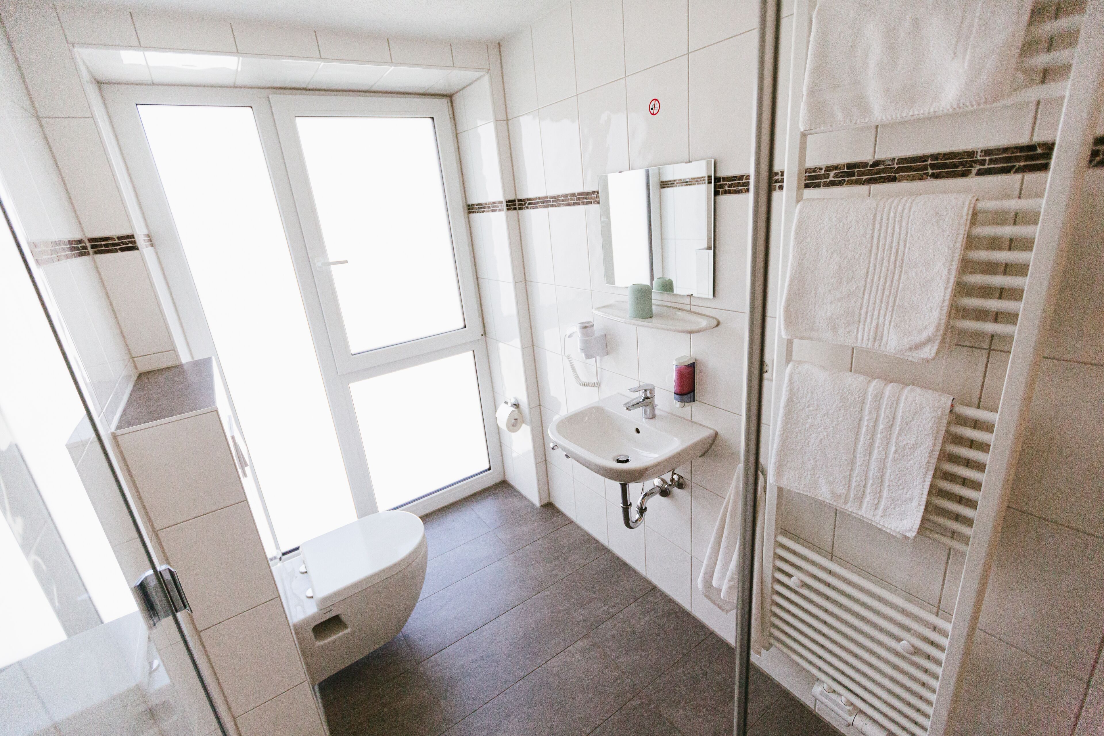 A modern bathroom with a toilet, sink, and glass shower enclosure.