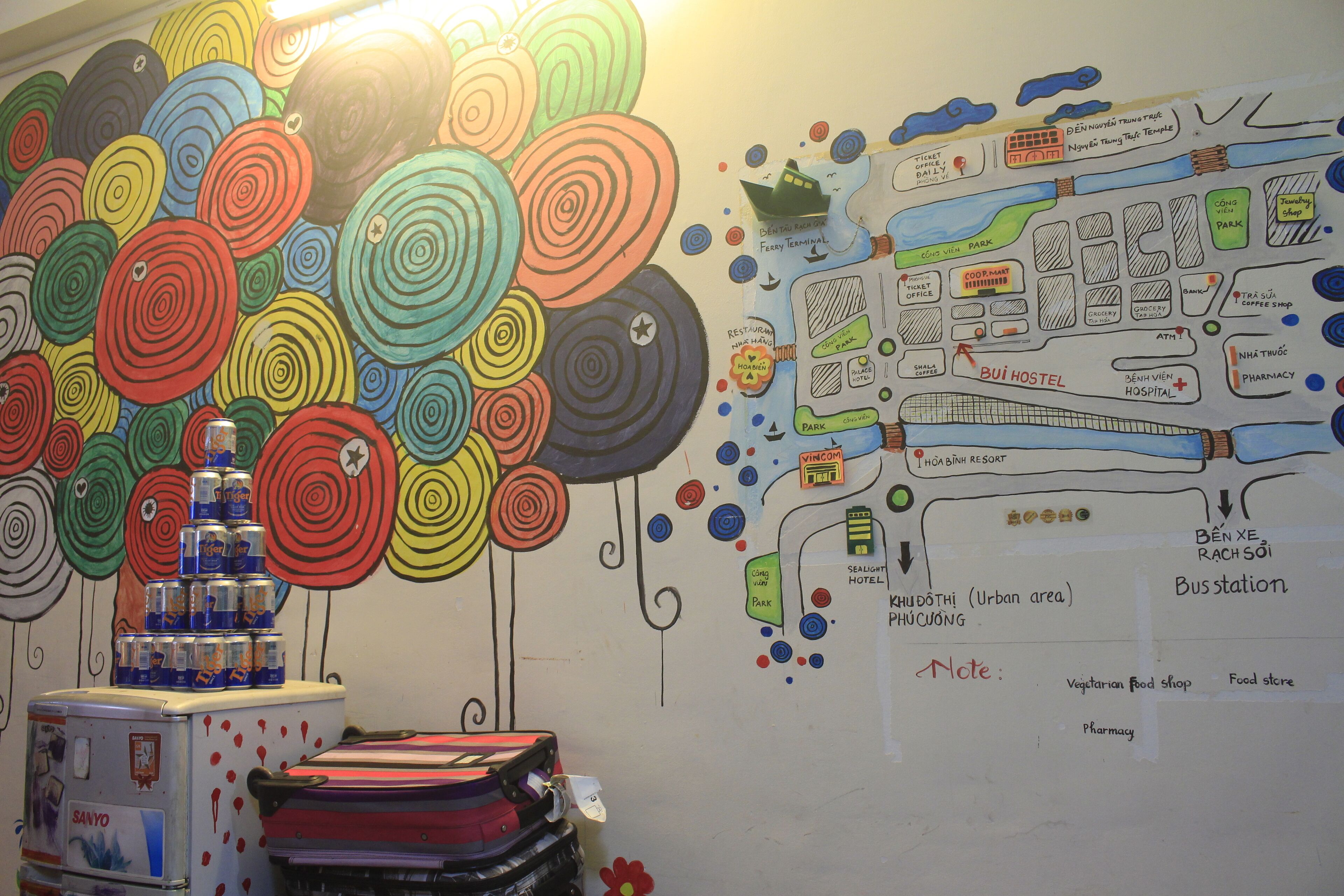 A colorful wall with a map and a refrigerator with drinks.