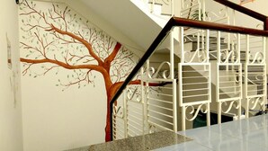 A staircase with a tree mural on the wall and a metal railing. - Bui Homestay - Rach Gia Ferry Terminal (Rach Gia)