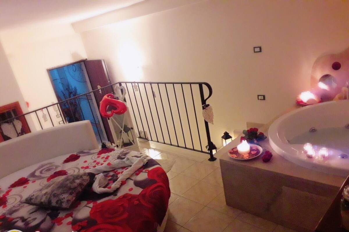 Un dormitorio con cama, una mesita con velas y una bañera.