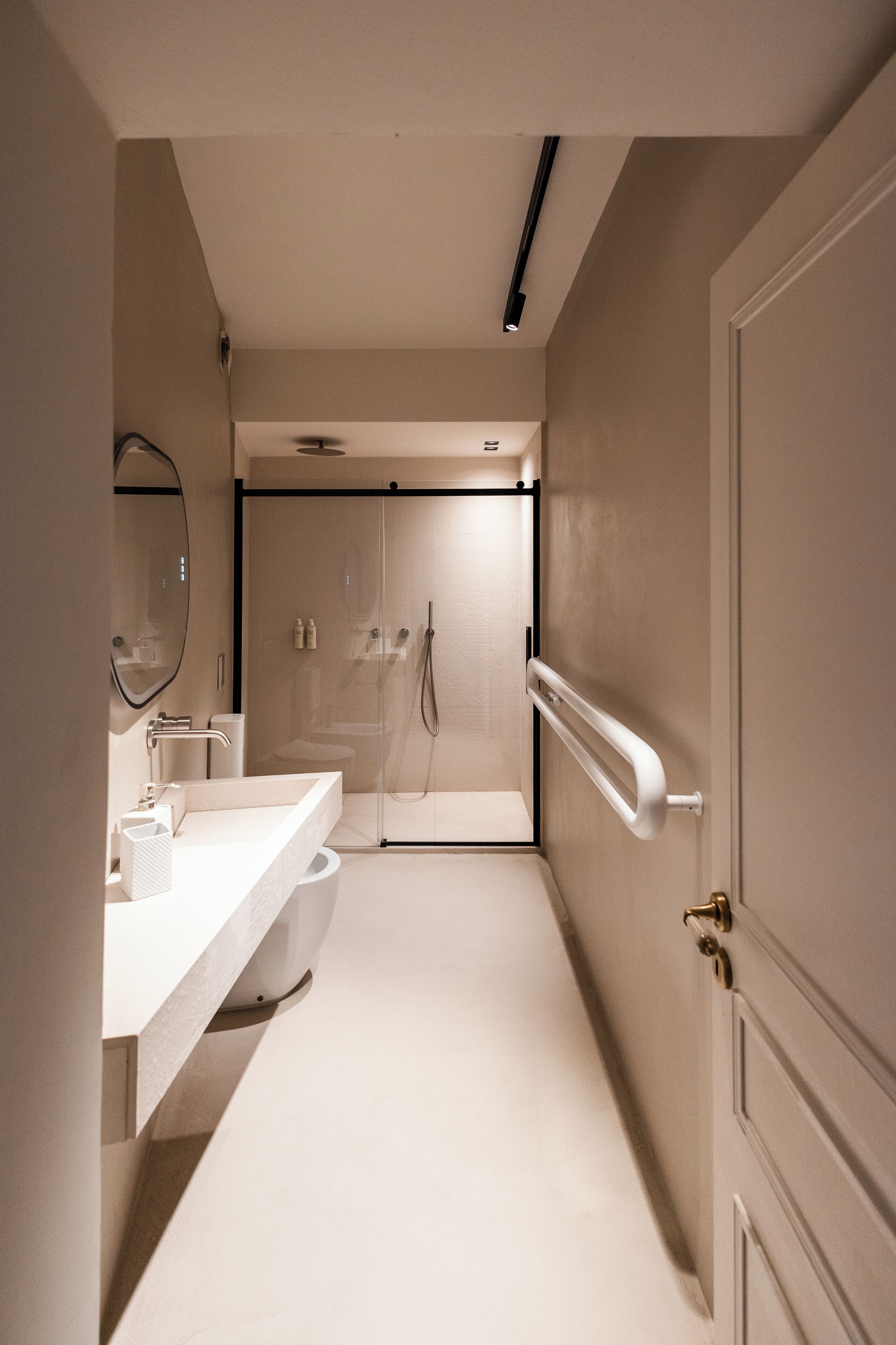 A modern bathroom with a white sink, mirror, and shower area.