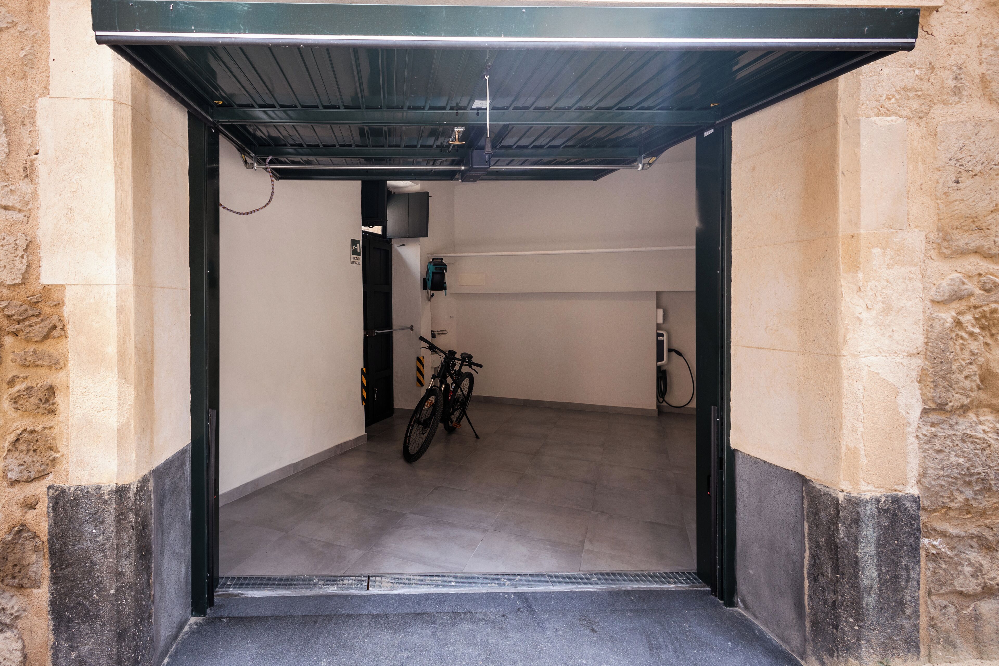 A covered bike parking area with a bicycle, a water station, and a wall-mounted device.