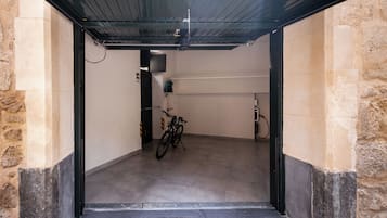 A covered bike parking area with a bicycle, a water station, and a wall-mounted device.