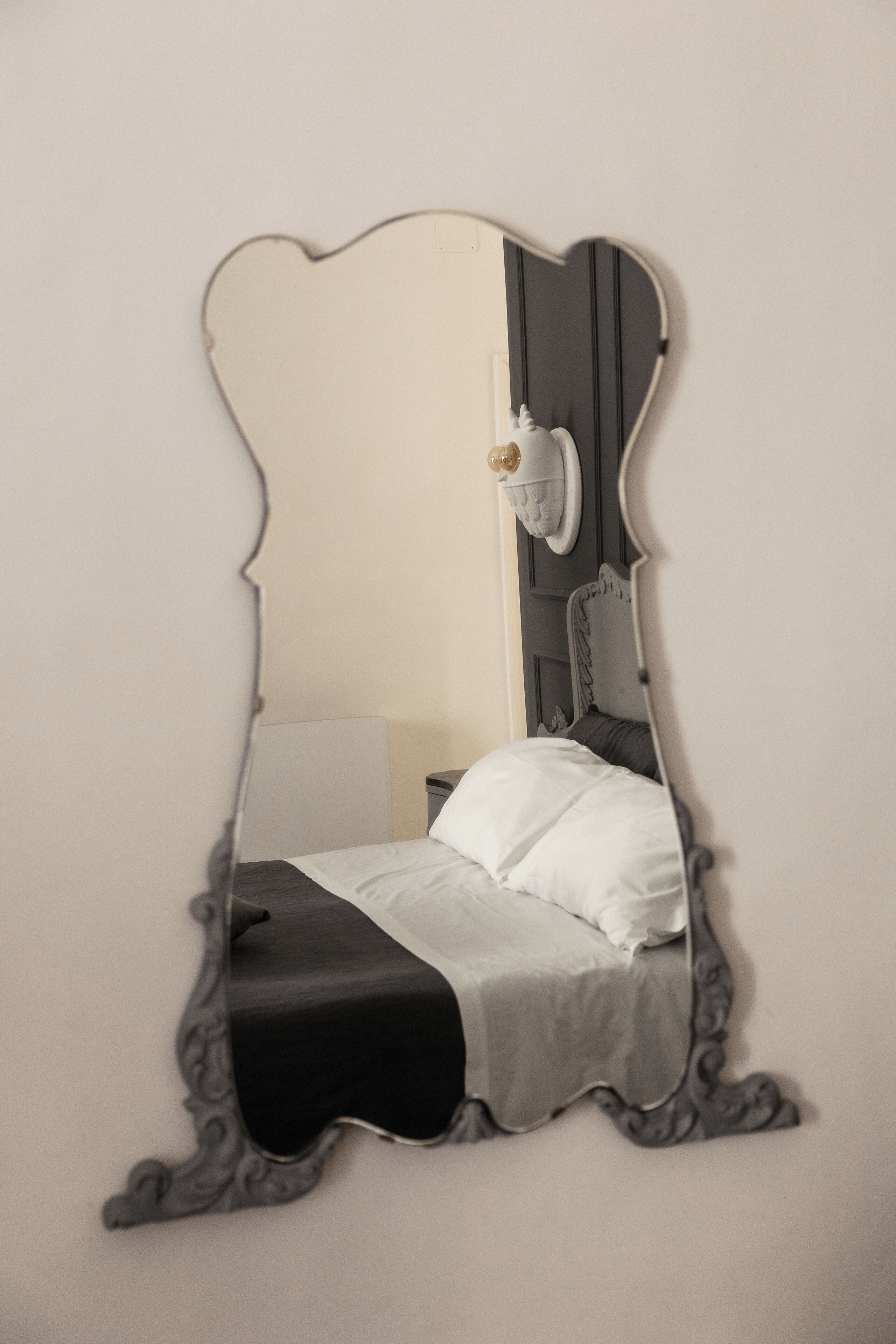 A bedroom with a bed, a nightstand, and a wall-mounted lamp.