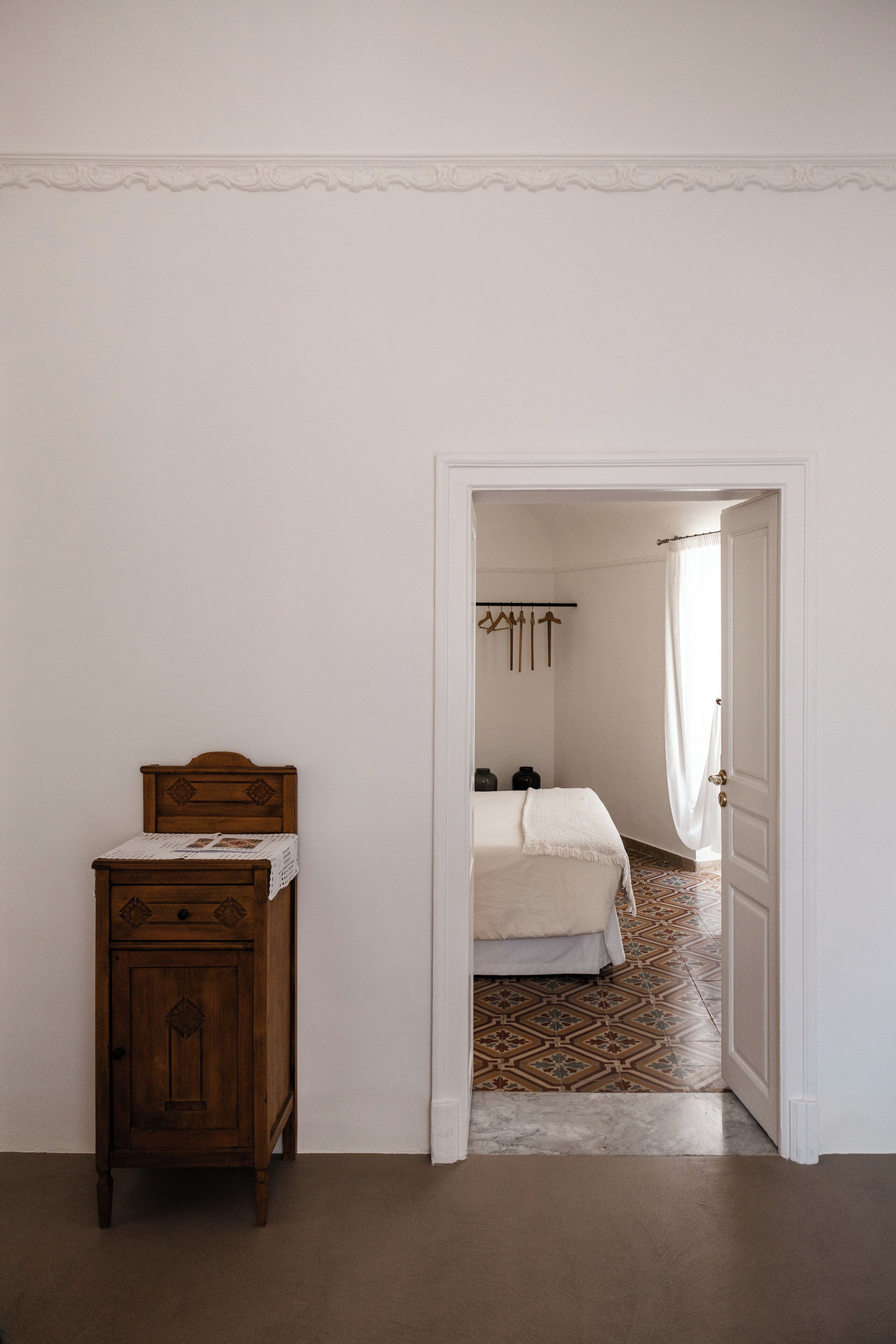 Una camera da letto con un letto in legno, una piccola credenza e un pavimento decorato.