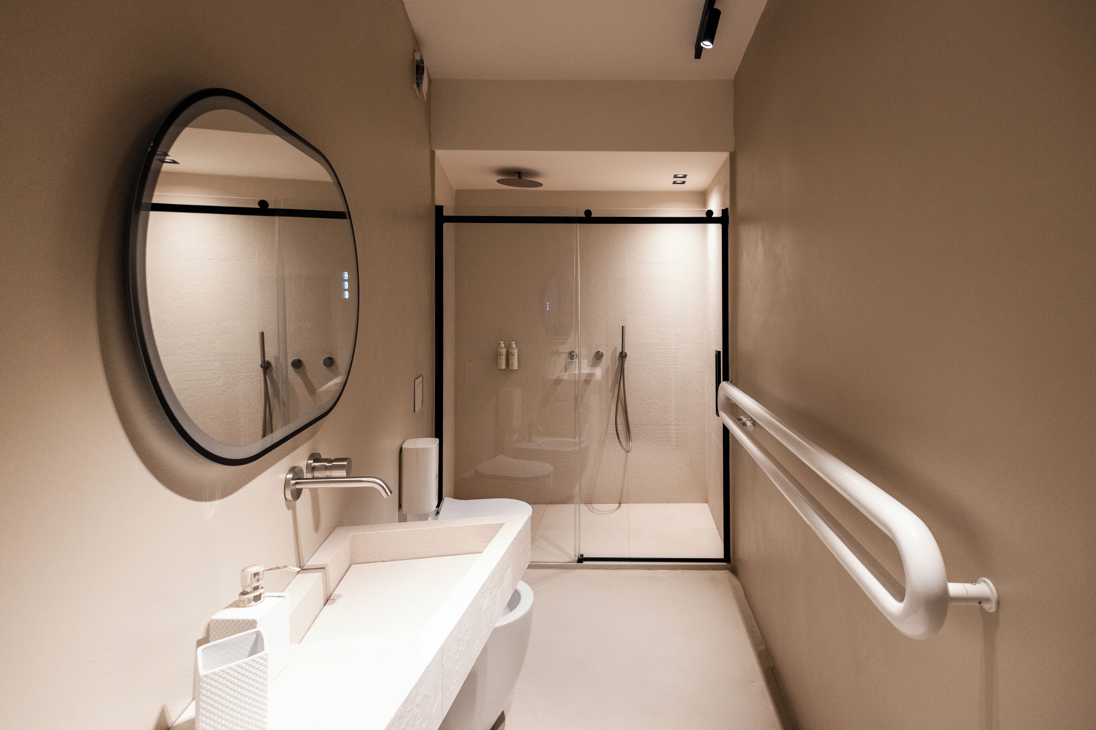 Une salle de bain moderne avec un grand miroir, un lavabo et une douche à parois de verre.