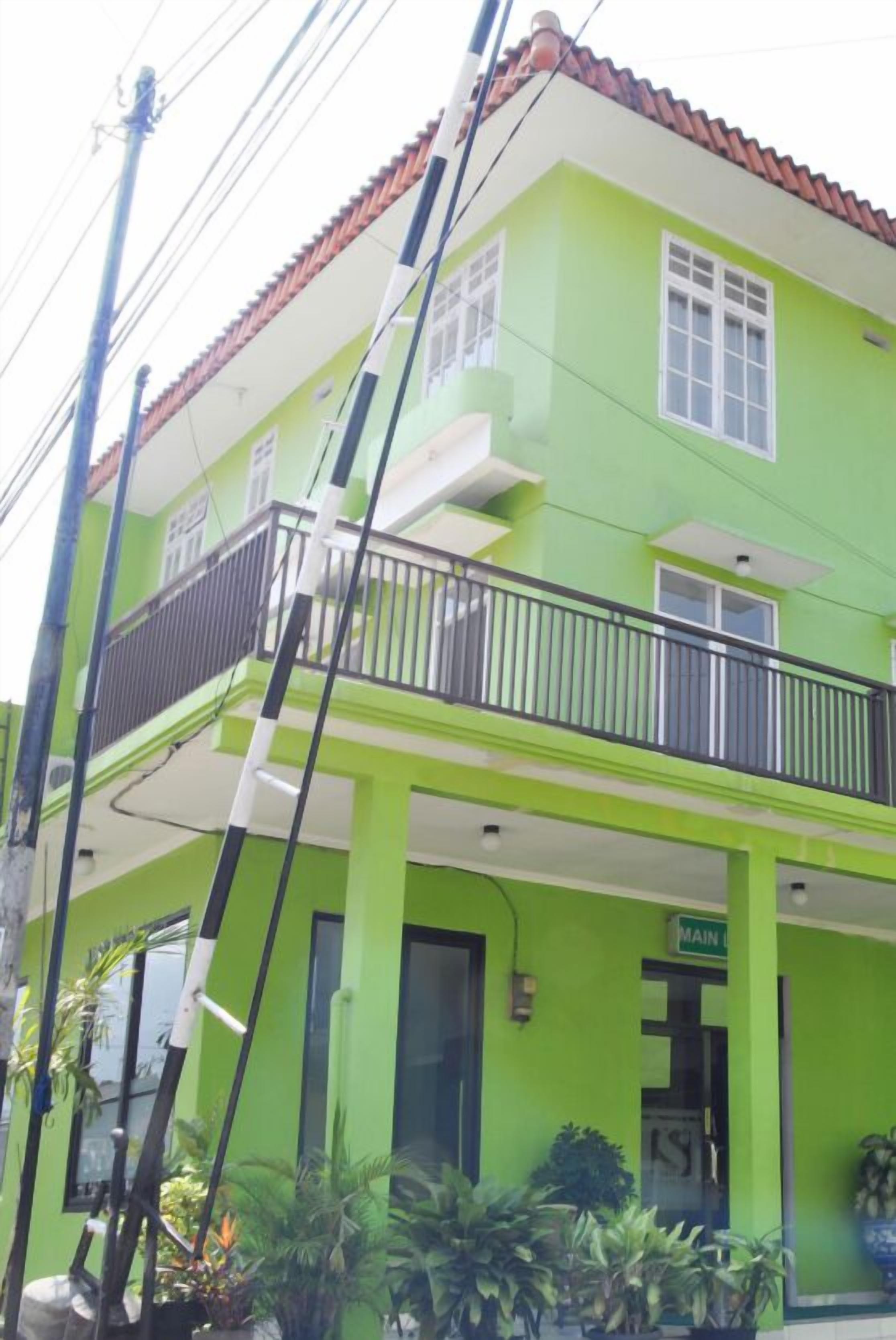 A green building with a balcony, a sign reading "MAIN", and a red-tiled roof.