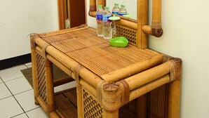 Un tocador de estructura de bambú con un espejo, un cuenco verde y botellas de agua.
