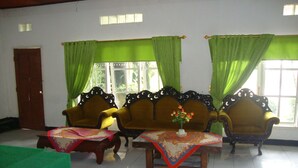 Una habitación con dos sillones elaborados, un sofá verde y una mesa con mantel decorativo.