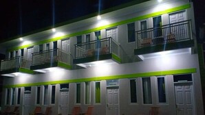 Un hotel de varios pisos con balcones y una fila de habitaciones con puertas y ventanas.