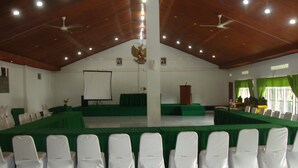 Un salón de conferencias con un escenario, un atril y filas de sillas.