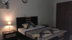 Un dormitorio con cama, mesita de noche con lámpara, espejo en la pared y armario.