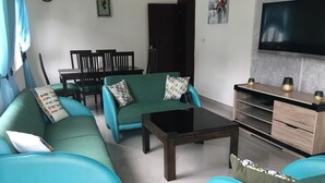 Una sala de estar con sofás color turquesa, una mesa de centro de madera y un televisor en la pared.
