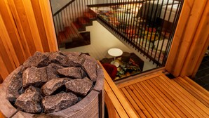 A stone fire pit in a wooden room with a view of a staircase and a red chair. - Amsterdam Plaza (Palanga)
