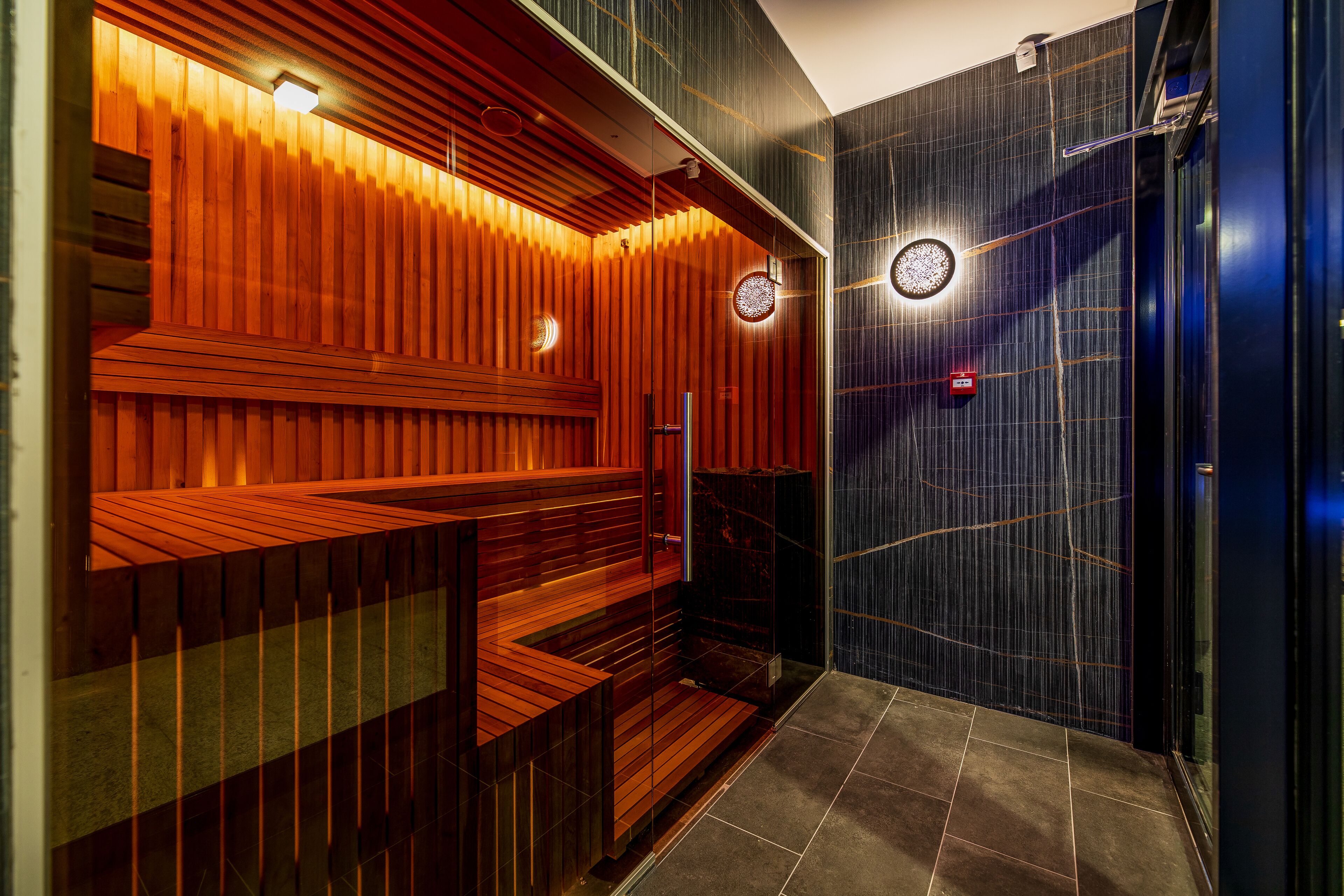 Una sauna moderna con bancos de madera y puerta de cristal.