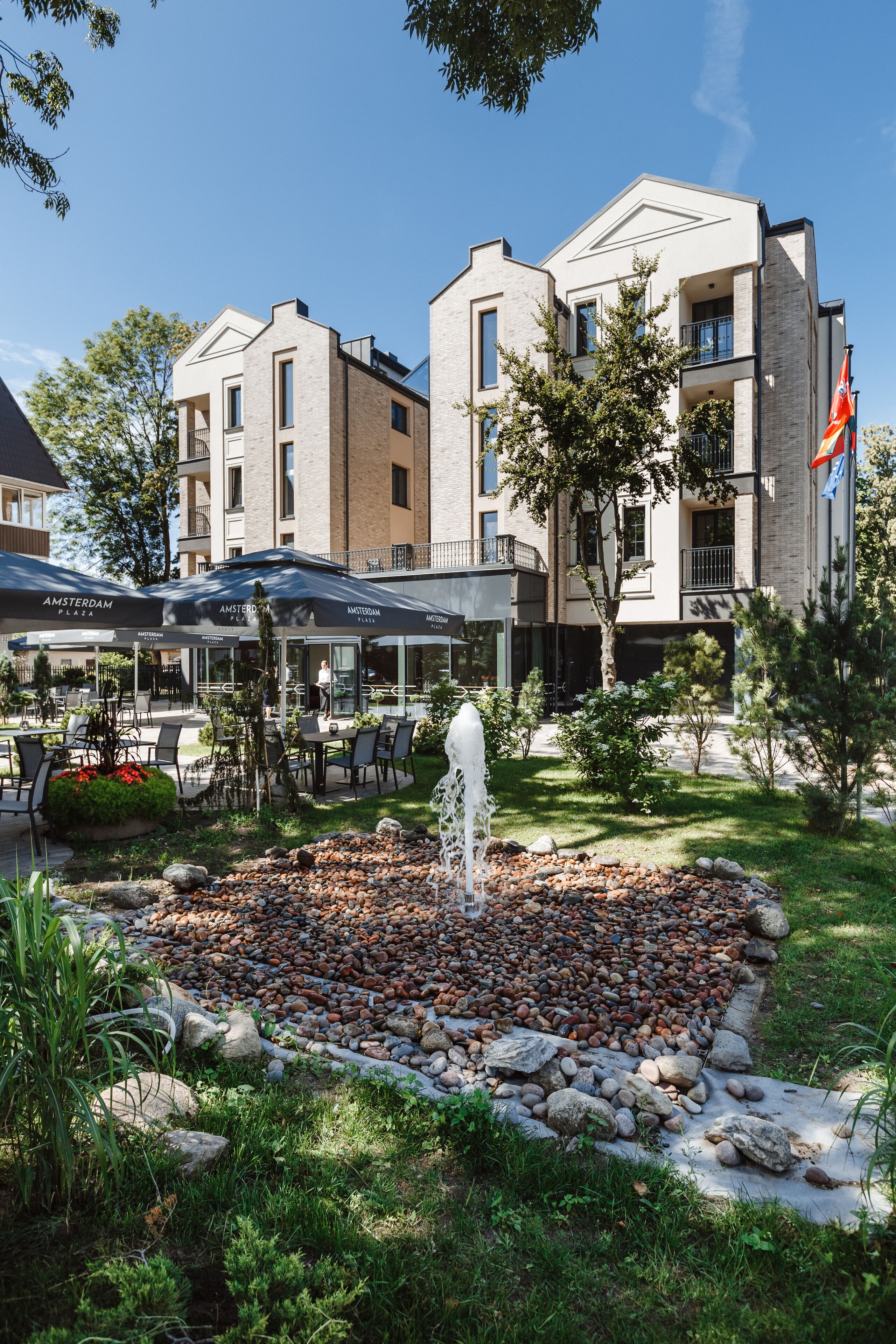 Un patio de hotel con mobiliario exterior, una fuente y una bandera.