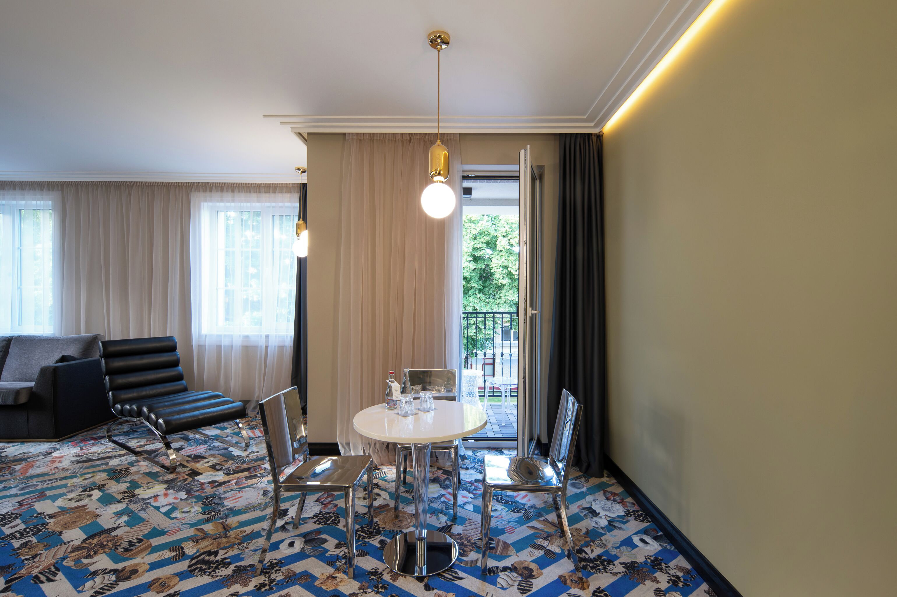 A hotel room with a dining area, a sofa, and a view of the outdoors.