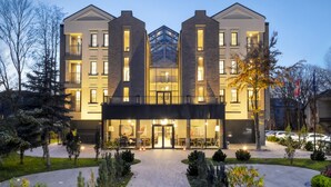 A modern hotel with a symmetrical facade, large glass windows, and a central entrance with a covered walkway. - Amsterdam Plaza (Palanga)