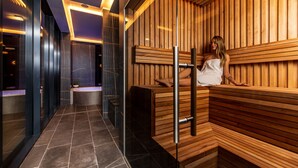 A modern spa with wooden paneling, a glass wall, and a bench. - Amsterdam Plaza (Palanga)