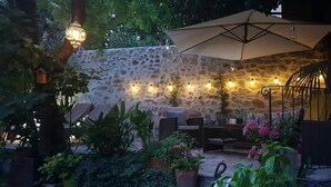 An outdoor patio with stone walls, string lights, and potted plants. - La Cordeline (Brignoles)