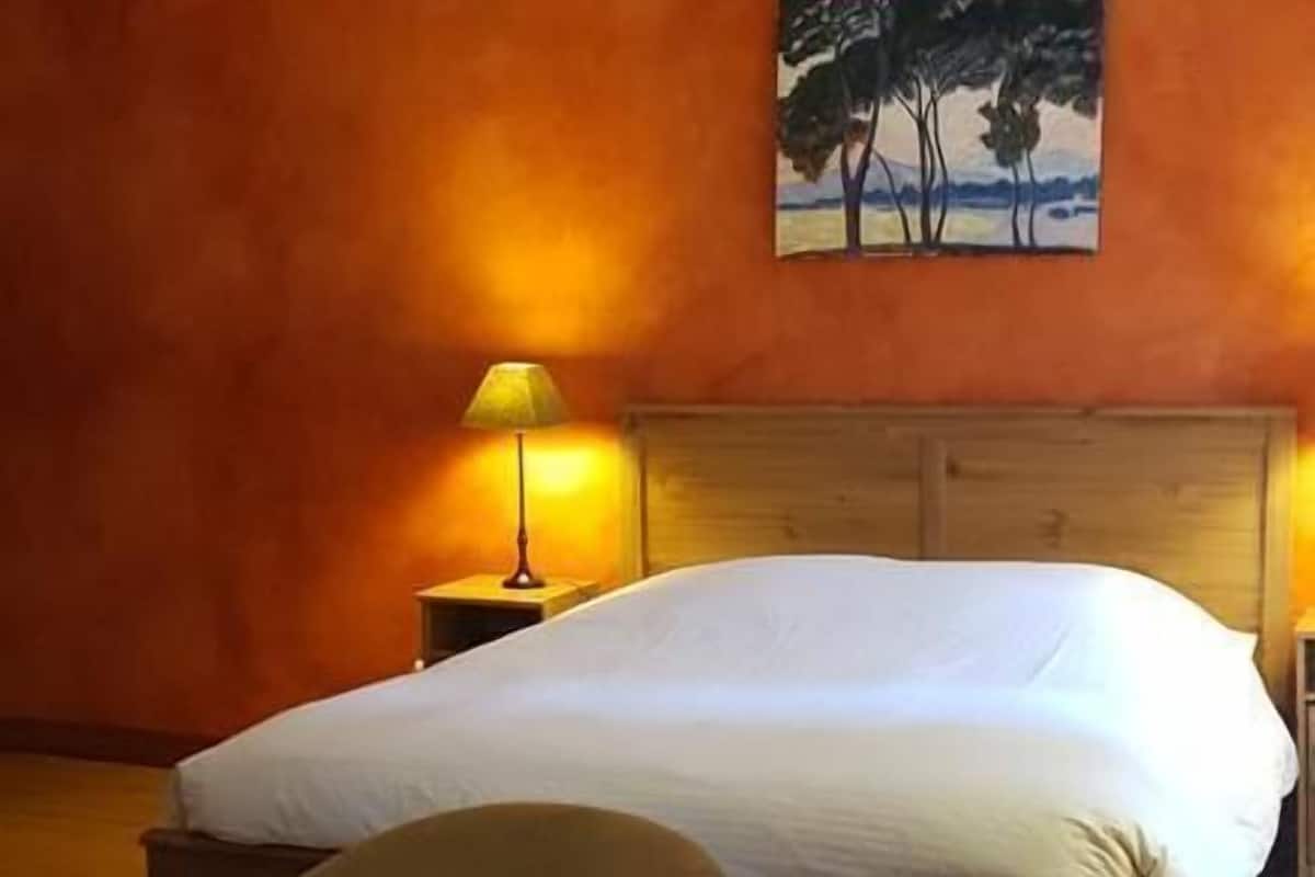 Un dormitorio con una cama de madera, una mesita de noche con una lámpara y una silla.