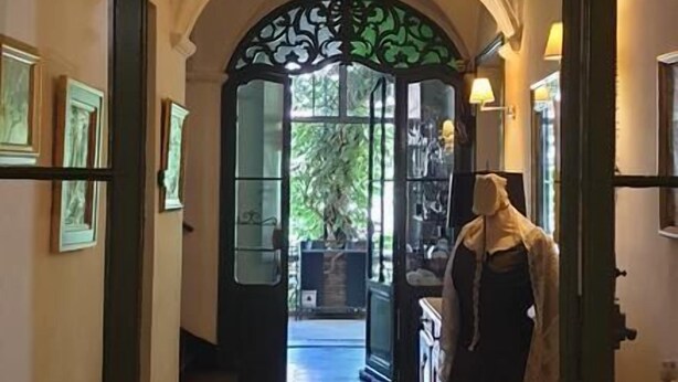 An ornate doorway leading to a room with a patterned floor and a mannequin dressed in a dark outfit. - La Cordeline (Brignoles)