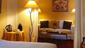 A hotel room with a bed, a sofa, two lamps, a painting, and a small table with a kettle and cups. - La Cordeline (Brignoles)