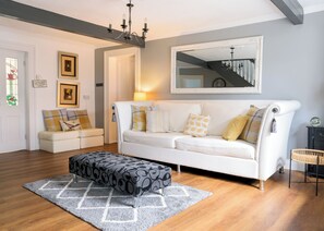 Relax in style with a comfortable sofa, matching ottoman, and elegant chandelier.