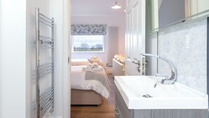 A modern bathroom with a large mirror, a white sink, and a shower area. - The Willows House & Studios (Limavady)