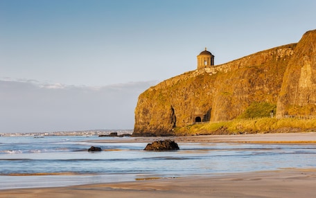A coastal landscape with a prominent cliff and a small building on top.