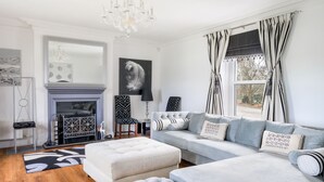A modern living room with a fireplace, a sofa set, and a chandelier.
