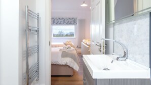A modern bathroom with a white sink, a mirror, and a towel rack.